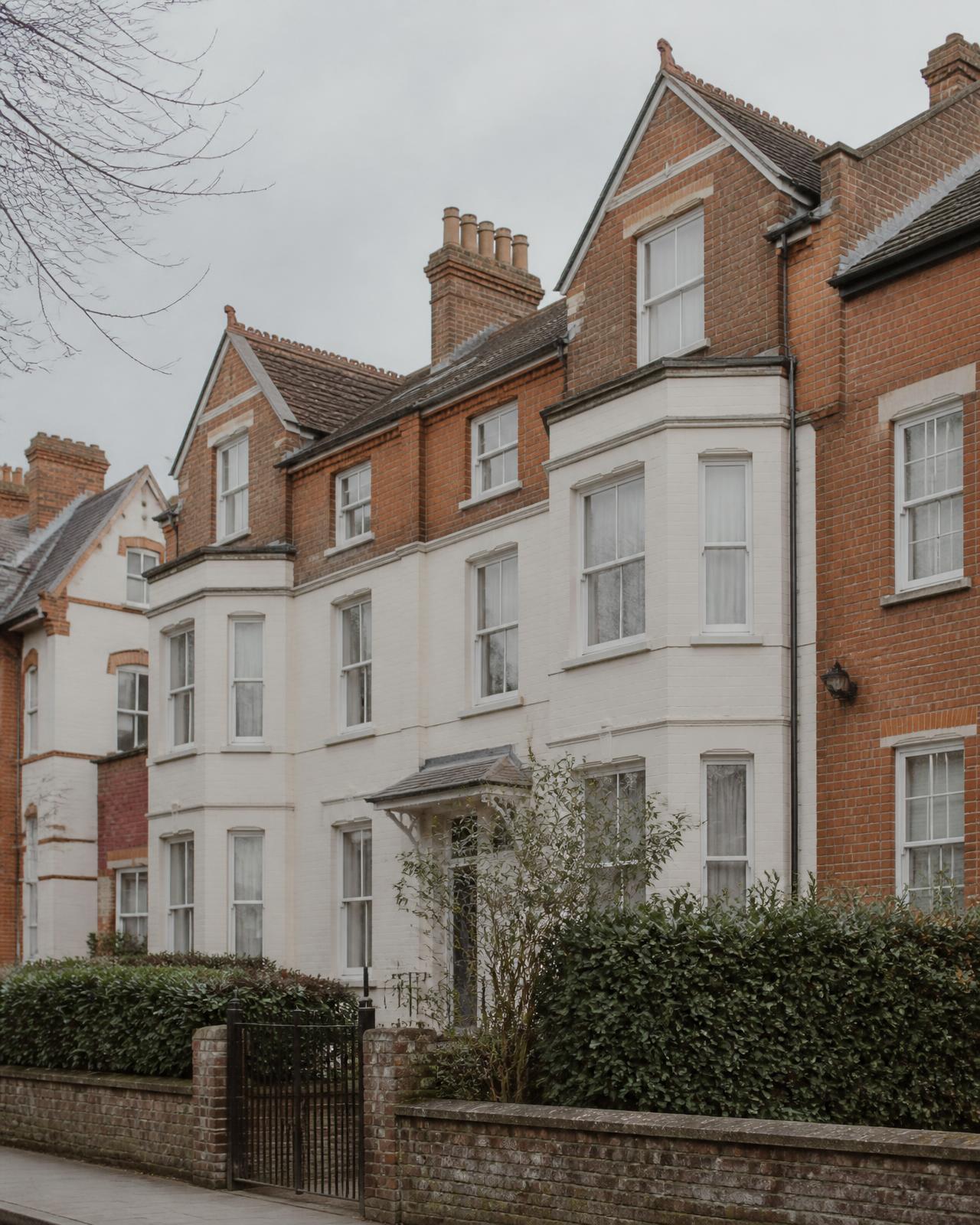 A row of British red-brick and painted residential townhouses in soft daylight